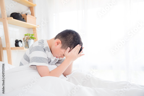 Young asian boy wake up with headache in the morning