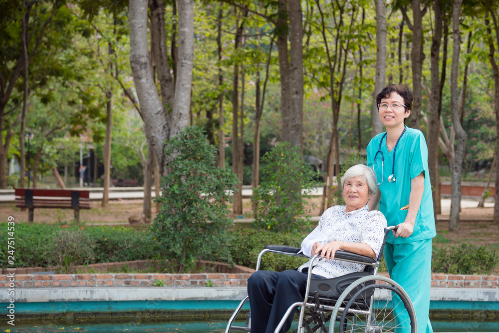 Happy asian senior woman on wheelchair with nurse in nursing home hospital garden Happy asian senior woman on wheelchair with nurse in nursing home hospital garden