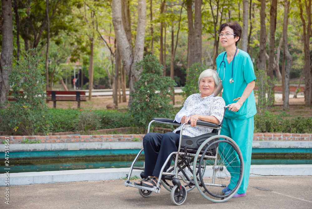Happy asian senior woman on wheelchair with nurse in nursing home hospital garden Happy asian senior woman on wheelchair with nurse in nursing home hospital garden