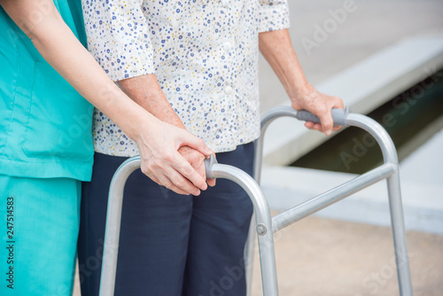 Close-up of disabled senior woman hand walking with assistance from nurse