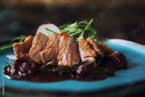 Duck confit with salad , baked apple and raspberry sauce served on wooden table