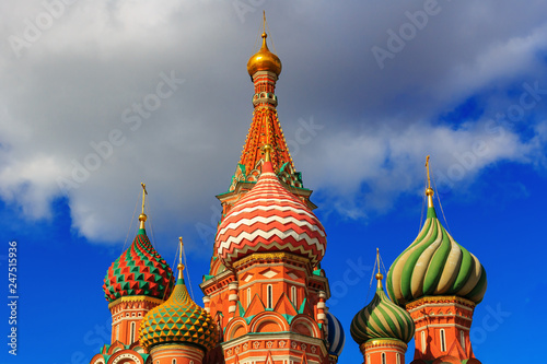Colored domes of St. Basil's Cathedral in Moscow against blue sky with clouds in sunny day