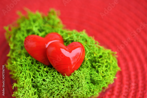 Valentines Day background with hearts. Hearts in green moss on red background