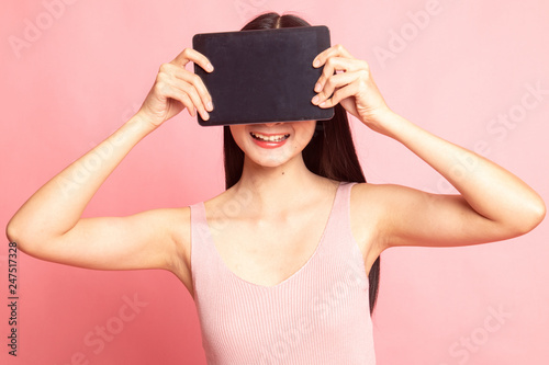 Young Asian woman with a computer tablet over her face.