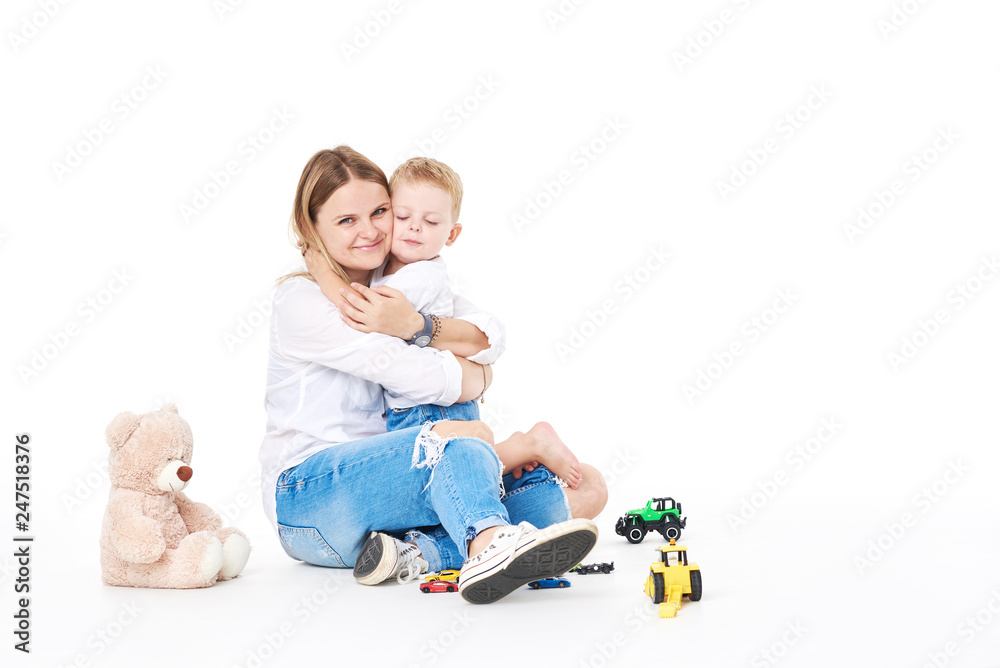 Motherhood concept. Young Mom and son play with plastic toys and cars. Excited preschooler playing with his smiling mother or kindergarten teacher. Isolated on white Motherhood concept. Young Mom and son play with plastic toys and cars. Excited preschooler playing with his smiling mother or kindergarten teacher. Isolated on white