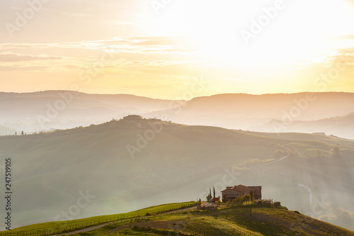 Morning fog in the rolling landscape with a house on a hill