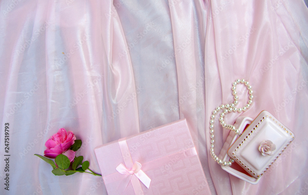 pink background with gift box and pearl beads and a rose, mother's day, symbols of love pink background with gift box and pearl beads and a rose, mother's day, symbols of love