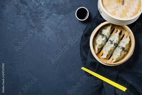 Korean dumplings in a traditional steamer  yellow chopsticks. Dark background  top view  space for text