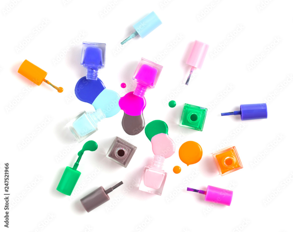 Nail art concept. Fine art cosmetics and beauty image of a group of colorful nail polish bottles on spilled paint isolated on white. Top view, flat lay Nail art concept. Fine art cosmetics and beauty image of a group of colorful nail polish bottles on spilled paint isolated on white. Top view, flat lay