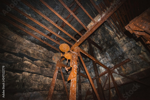 Inside old closed coal mine; dangerous tunnels full of dirt, lots of abandoned rusty equipment, devastated industrial place
