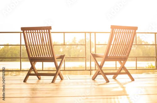 Balcony view at sunset with wooden chairs. Interior design of resort at holiday travel