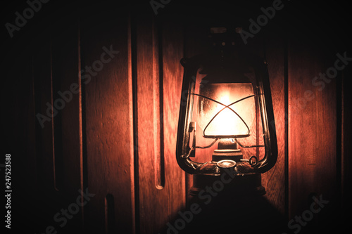 Burning kerosene old lamp on bamboo wooden, lighting in camping night
