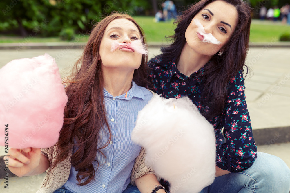 Two cheerful girls having fun with cotton candy outdoor Two cheerful girls having fun with cotton candy outdoor