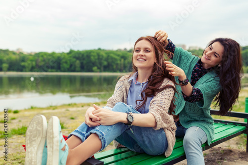 Two beautiful girls relaxing while making hairdo enjoying time together
