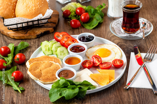 Huge healthy breakfast spread on a table with coffee, tea, tomato, egg, pancake, jam and cheese,