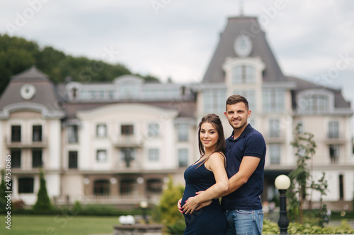 Pregnant woman and her husbant hug each other and smile. Man put his hand of belly of pregnant woman. Six months of pregnancy