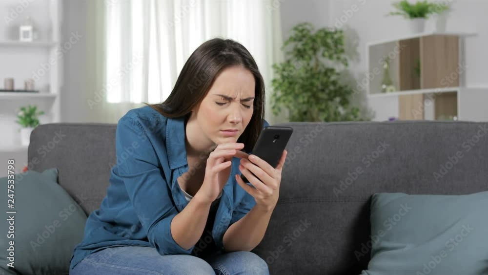 Woman suffering eyestrain using smart phone sitting on a couch at home Woman suffering eyestrain using smart phone sitting on a couch at home