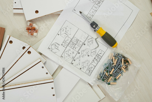 The furniture assembler joins together the two parts of the ready-to-assemble furniture with cam lock connections and wooden dowel pin, flat pack furniture assembly service, snap-together joints photo