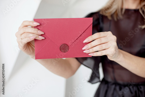 Close-up woman with slim body holding invitation envelope card in hands, rear veaw.