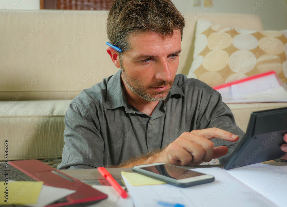 young attractive and happy freelance business man with calculator and laptop doing domestic accounting paperwork of domestic payments taxes and monthly money income