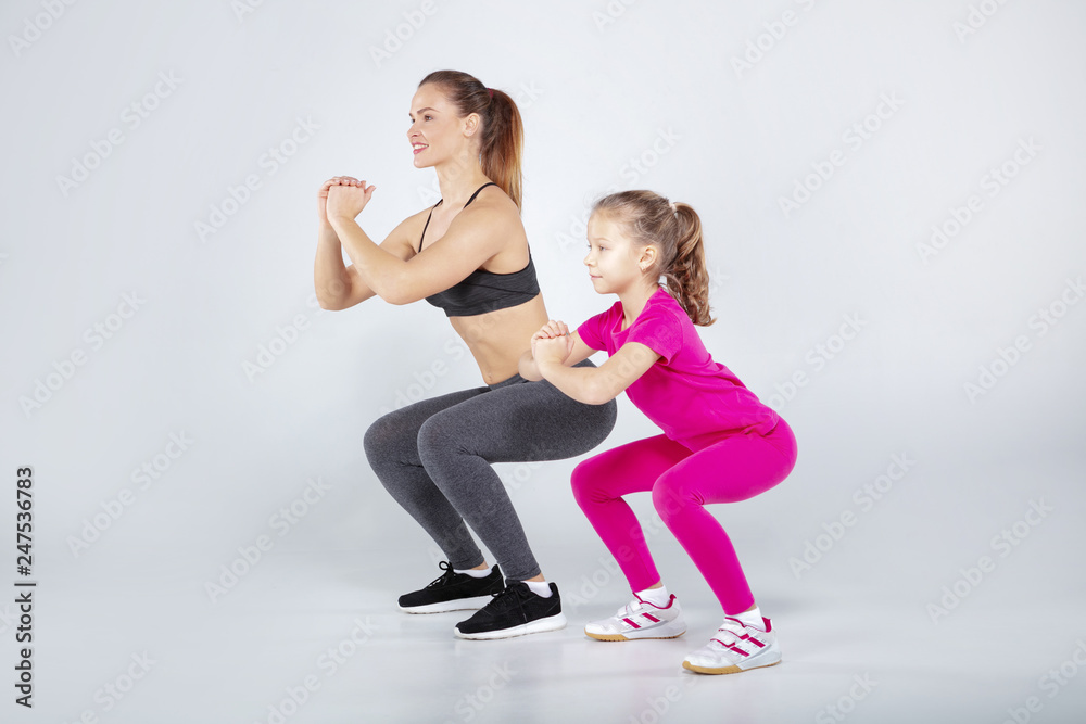 Female trainer and 10 years old girl are doing gym exercises