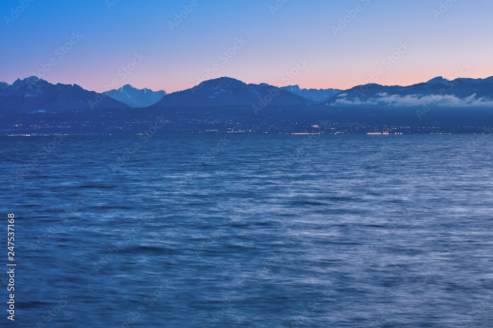 Early morning on the shores of Lake Geneva, clear sky and blue mountains