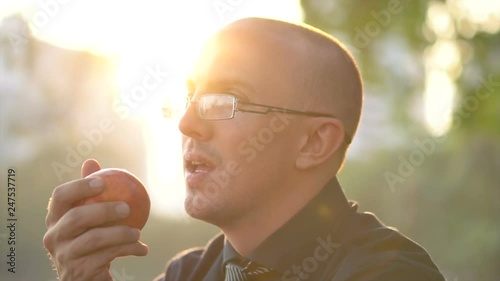 Young Man Eating Red Apple Outdoors in Park  photo