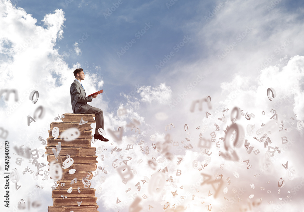 Man student on stack reading book and symbols flying around Man student on stack reading book and symbols flying around