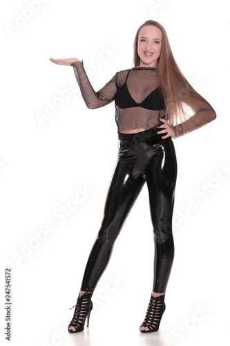 Young woman in black shiny leggings and net blouse on white background, holding imaginary object