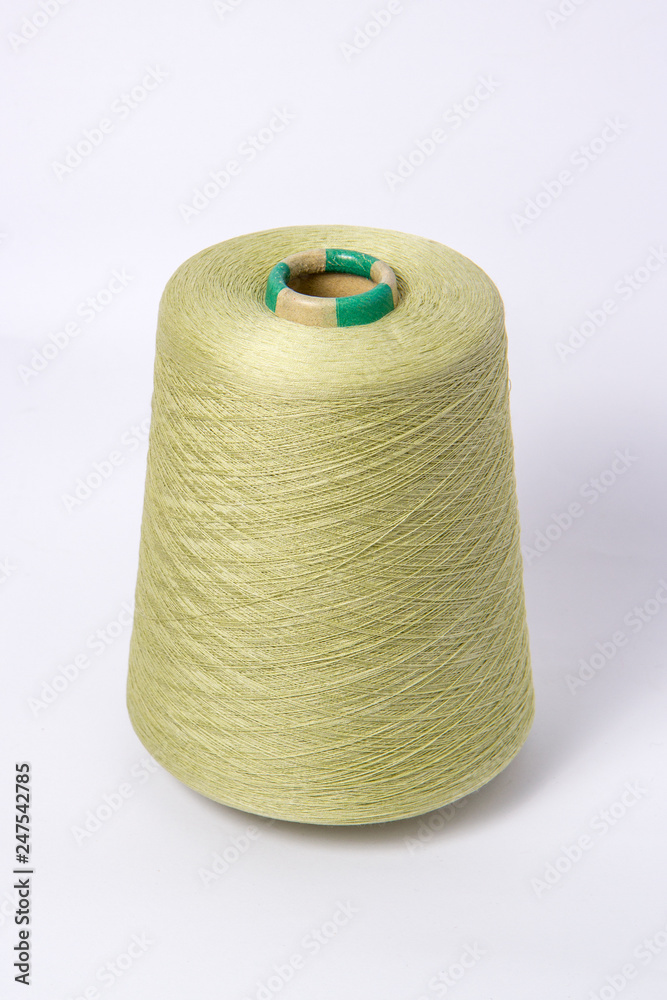 Green bobbin of yarn on a white background.Textile reel on isolated white background. Green bobbin of yarn on a white background.Textile reel on isolated white background.