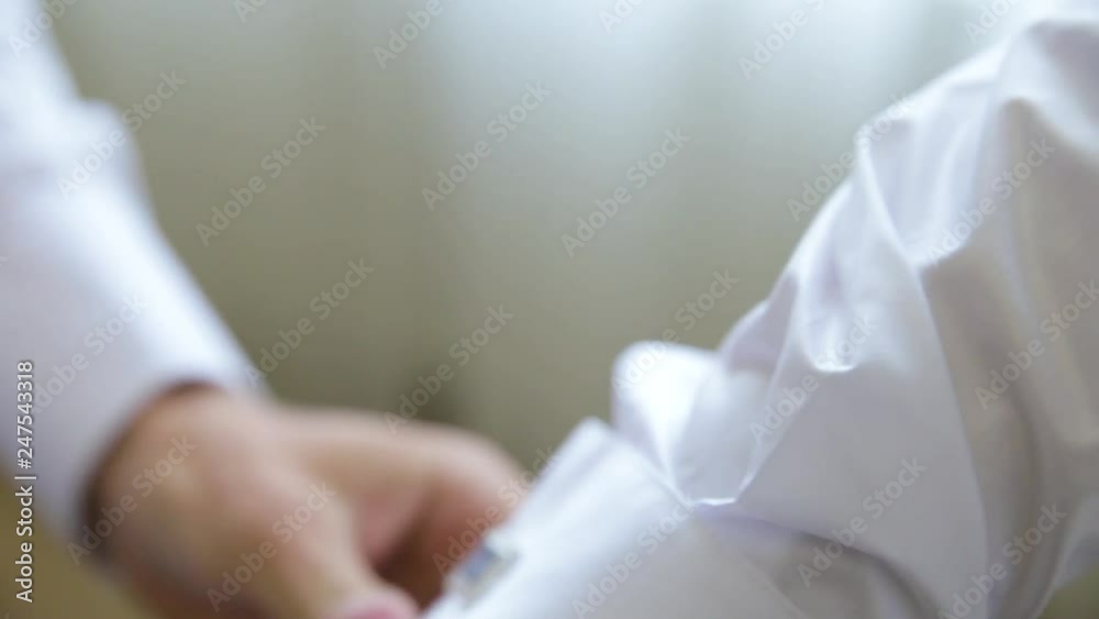 Elegant young fashion man gets cufflinks, dressing up for wedding celebration. Elegant young fashion man gets cufflinks, dressing up for wedding celebration.