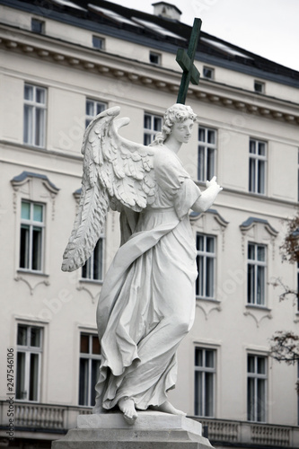 Angel statue with cross in front of Karlskirche church in Vienna, Austria