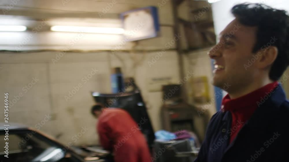 Car mechanic greets customer and returns his car keys in the garage, in slow motion Car mechanic greets customer and returns his car keys in the garage, in slow motion