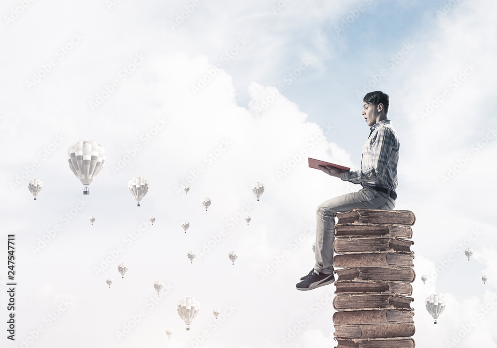 Man student on stack reading book and aerostats flying around Man student on stack reading book and aerostats flying around