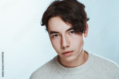 Studio portrait young man in grey sweater on white background