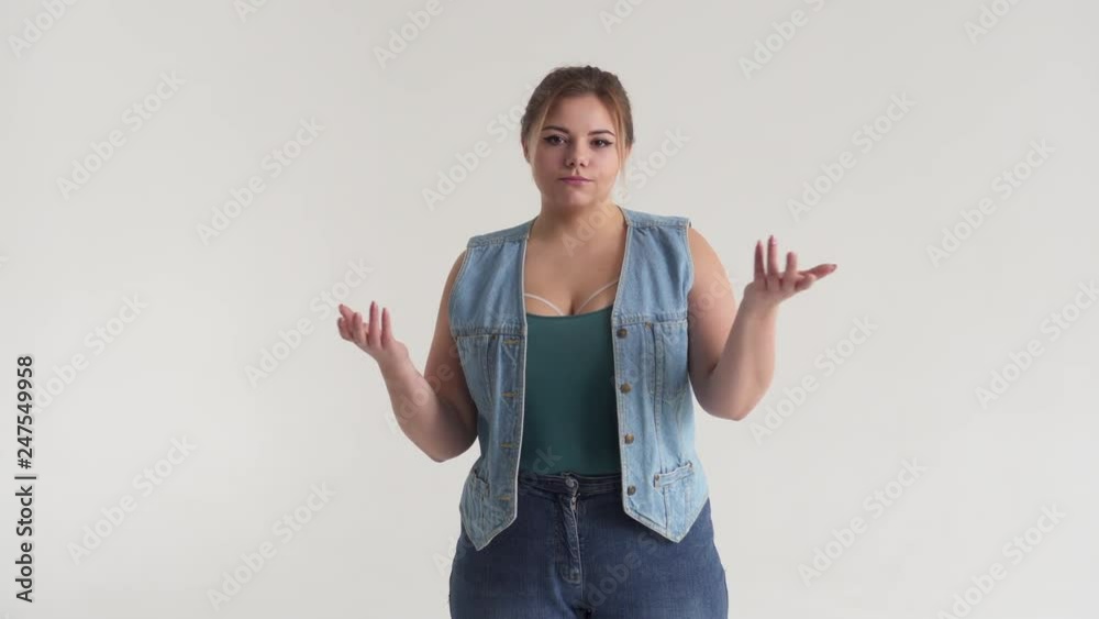 Disappointed young woman gesturing with her arms out and shaking head in denial Disappointed young woman gesturing with her arms out and shaking head in denial