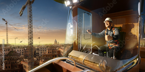 Engineer operator crane in action . He sit a top in crane cabin and working. Around beautiful sunset photo