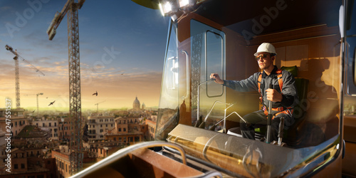 Engineer operator crane in action . He sit a top in crane cabin and working. Around beautiful sunset