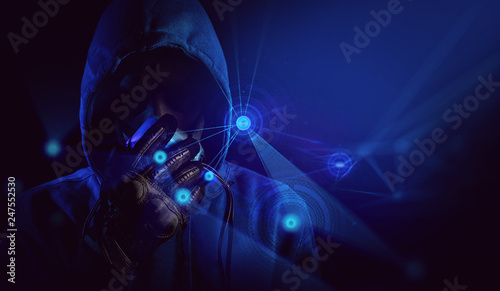 bad guy hacker with blue hood outfit and mask with glove on dark background in security virus network hologram concept