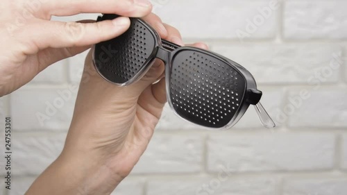 Looking at pinhole glasses. Obscura glasses in female hands.