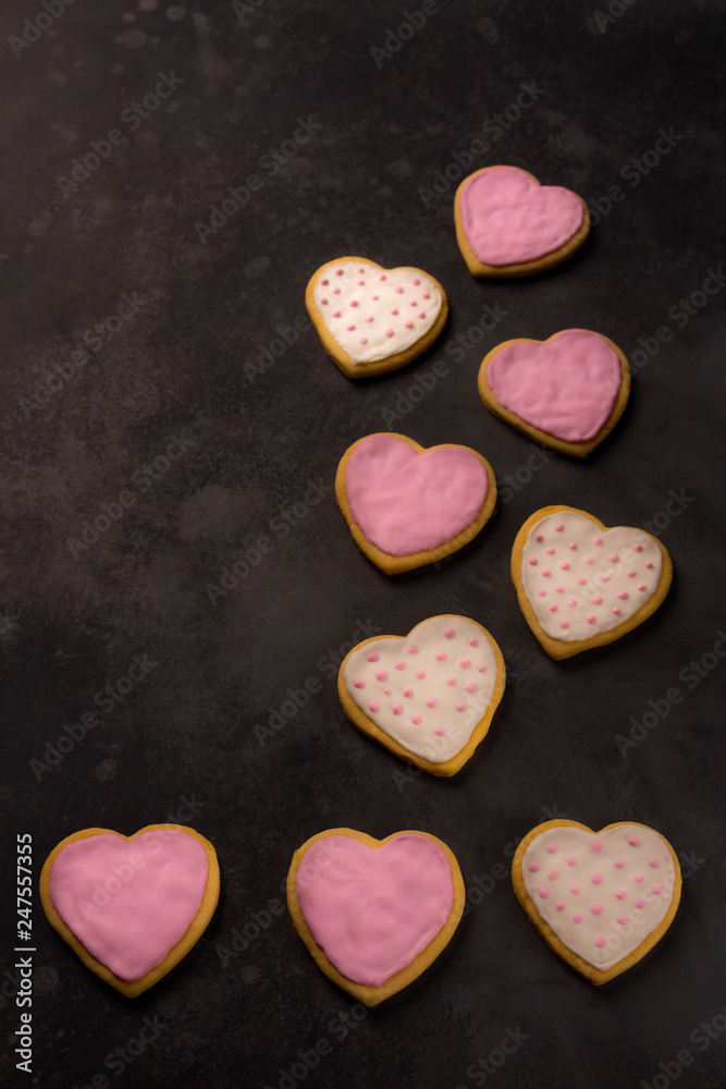 Obraz premium heart shaped sugar cookies with white, pink icing, dark background
