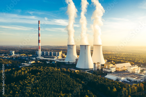 A Power plant with white smoke over it's chimneys
