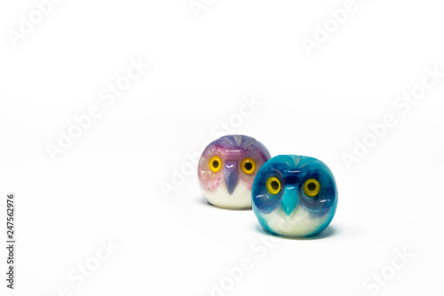 Lucky owl ornament. Small glass lucky object, charm. Blu, azzurro, lilla, viola, giallo. Isolated on white background. Tradition has it that a pair (couple) of owls bring luck.