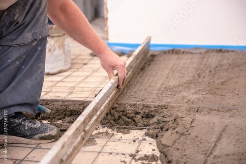 bricklayer aligns cement screed in a newly built house