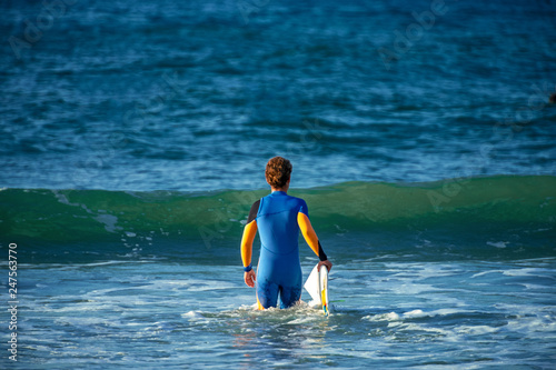 12/18/2018 Netanya, Israel, a surfer with a board goes swimming in the ocean at the dawn of the day