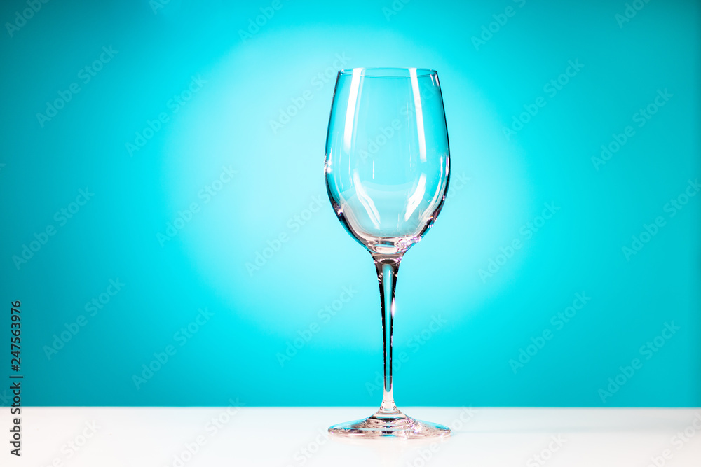 Clear drinking glass isolated on cyan blue background.