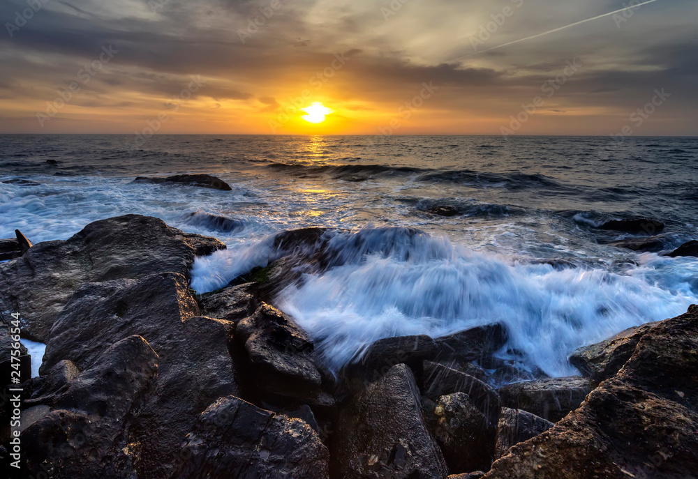 Obraz premium Stormy sea with the colorful sunrise sky at the rocky coastline of the Black Sea