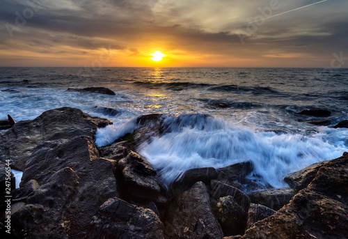 Stormy sea with the colorful sunrise sky at the rocky coastline of the Black Sea