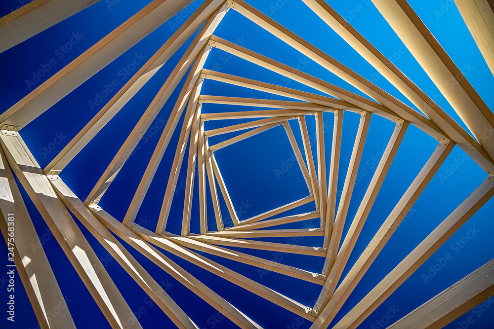 .swirled ceiling of a wooden gazebo on the background of blue and clear sky