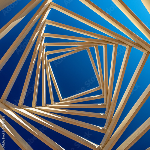 .swirled ceiling of a wooden gazebo on the background of blue and clear sky